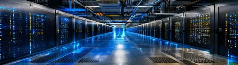 Panoramic view of a row of dark server racks in a data centre cold aisle, blue and amber LED indicator lights running down each cabinet, polished anti-static floor reflecting the lights, perforated tile vents, no people no faces no hands