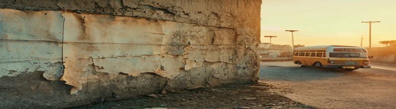 Panoramic wide-angle photograph of a sun-bleached recruitment poster peeling from a concrete wall in an unnamed African city, faded paper, dusty street, distant minibus, late-afternoon light, documentary realism, no people no faces no hands